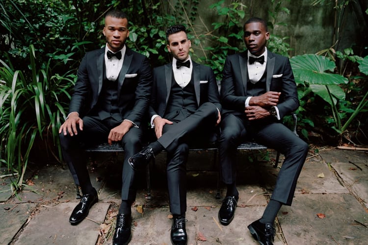 Three men in tuxedos on a bench